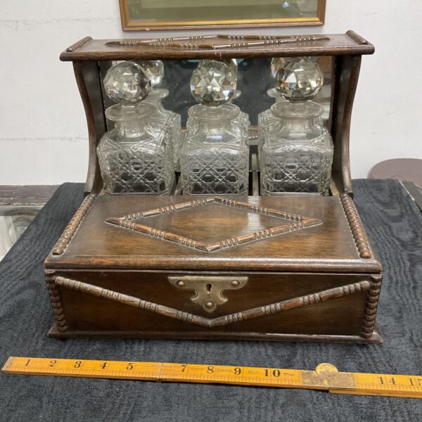 Antique Victorian Tantalus with three crystal decanters and oak cabinet.
