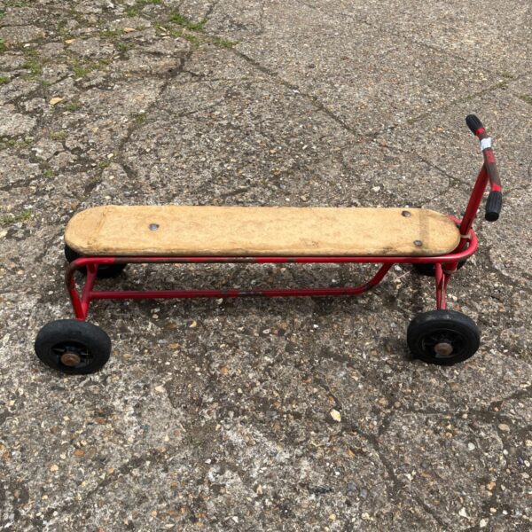 Vintage red metal children's double seat scooter with wooden platform.