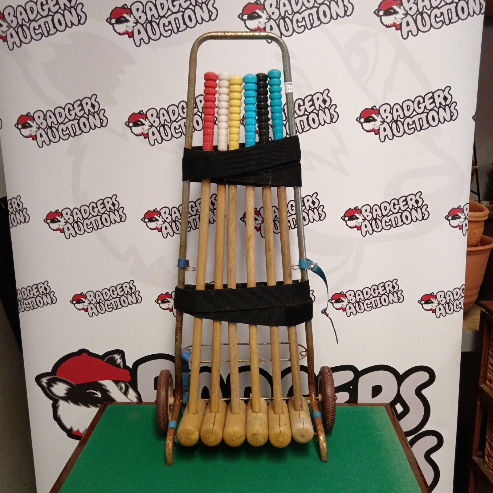 Vintage croquet set with mallets on a metal trolley in a garden setting.