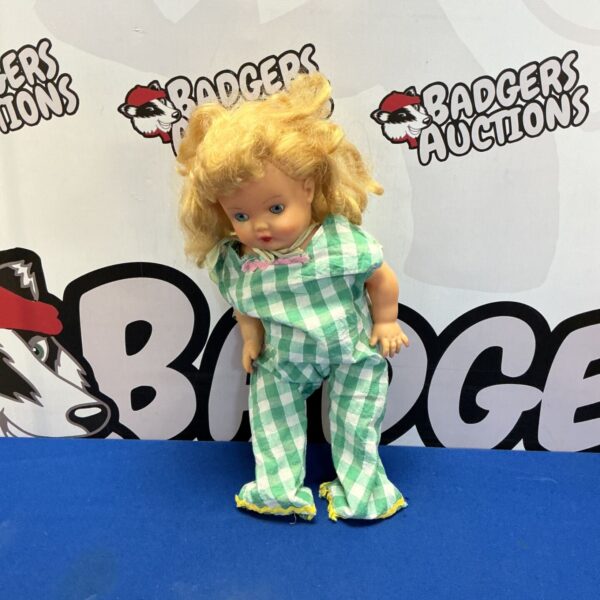 Vintage doll with moving eyes in green playsuit.