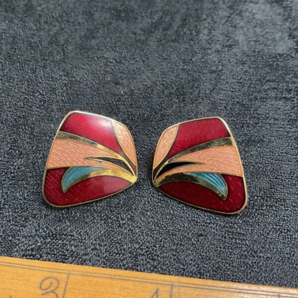 Close-up of vintage enamel butterfly earrings with red and teal details.