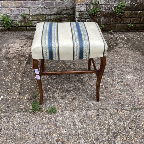 Vintage foot stool with blue and cream patterned upholstery.