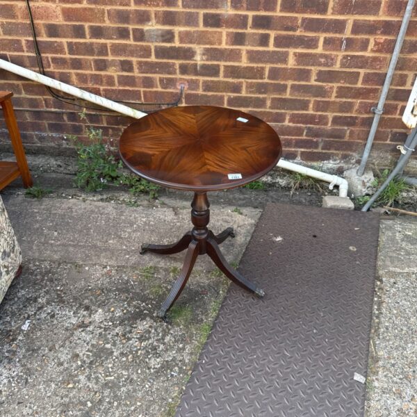 Vintage mahogany pedestal table with a round top and curved feet.
