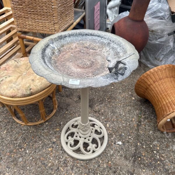 Vintage metal bird bath with a fibreglass bowl in a garden setting.