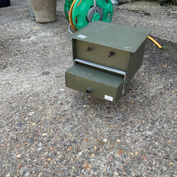Vintage metal chicken feeder box in a garden setting.