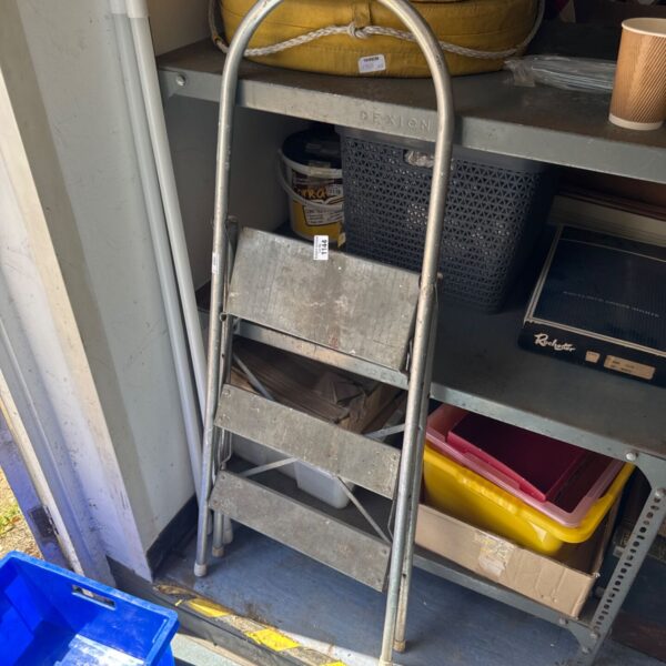 Vintage metal three-tier folding step ladder in a workshop setting.