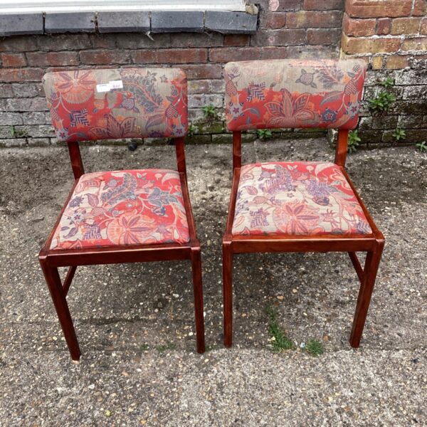 Vintage mid-century dining chairs with floral upholstery and teak frames.