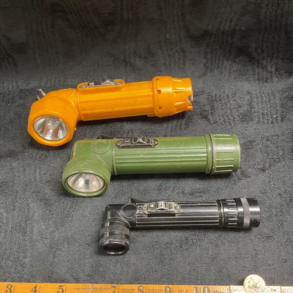 Three vintage military torches in orange, green, and black.