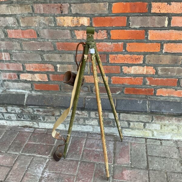 Vintage military tripod with leather sling, antique field equipment.