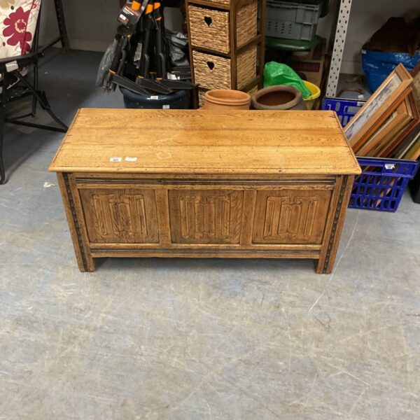 Vintage oak blanket chest with a paneled front and hinged lid.