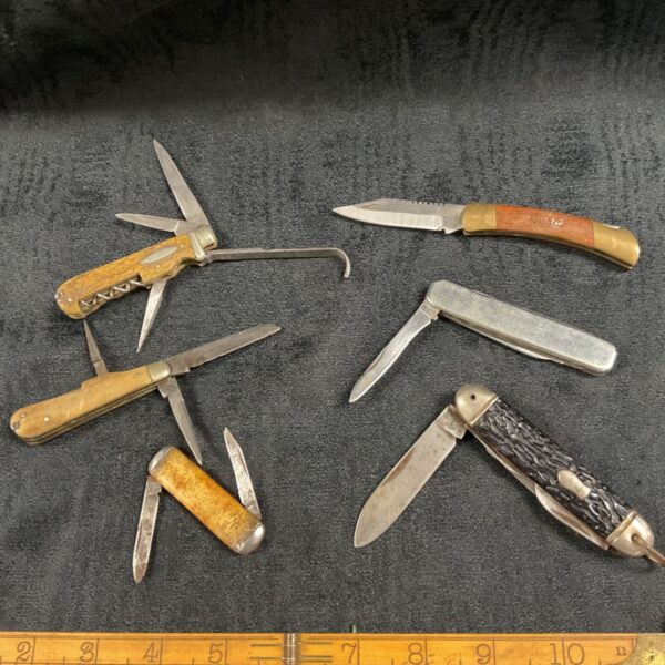 Six vintage pocket knives with bone and wood handles displayed together.