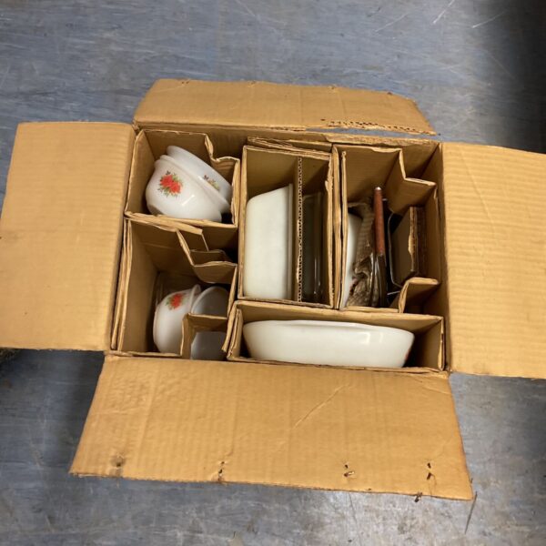 Vintage Pyrex casserole dishes with a floral pattern in a cardboard box.