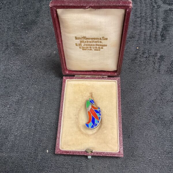 Close-up of a vintage silver enamel brooch with red, white, and blue details.