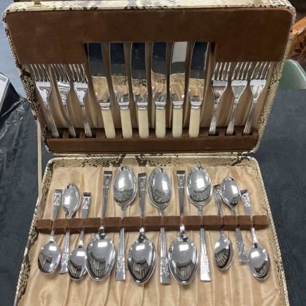 Open vintage snakeskin canteen revealing stainless steel cutlery set.