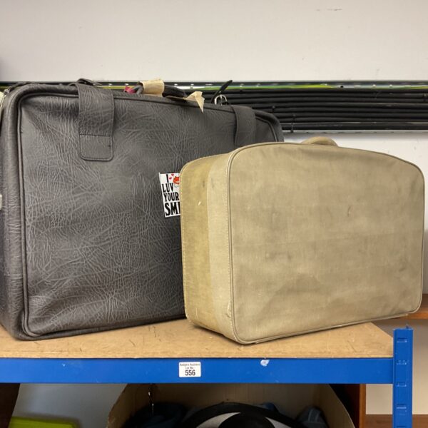 Lot of two vintage brown suitcases on a shelf.