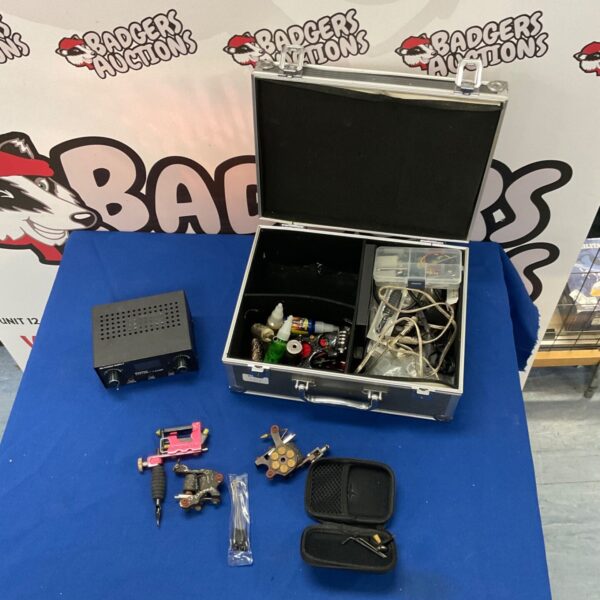 Open vintage tattoo kit displaying tattoo machines and supplies.