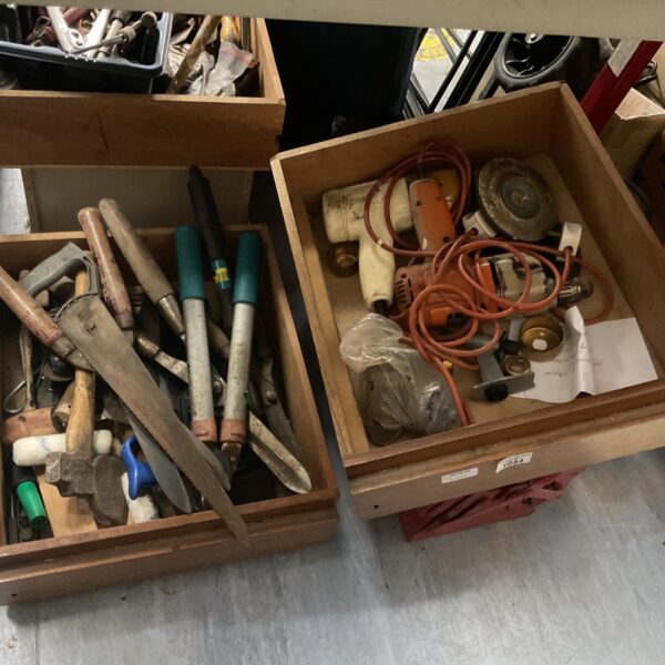 Vintage tool lot with saws, drills, and axe in wooden box.