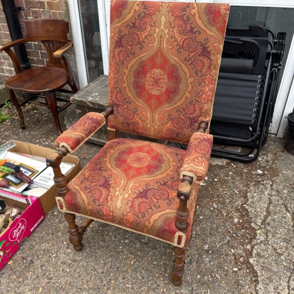 Vintage upholstered armchair with red and gold patterned fabric.