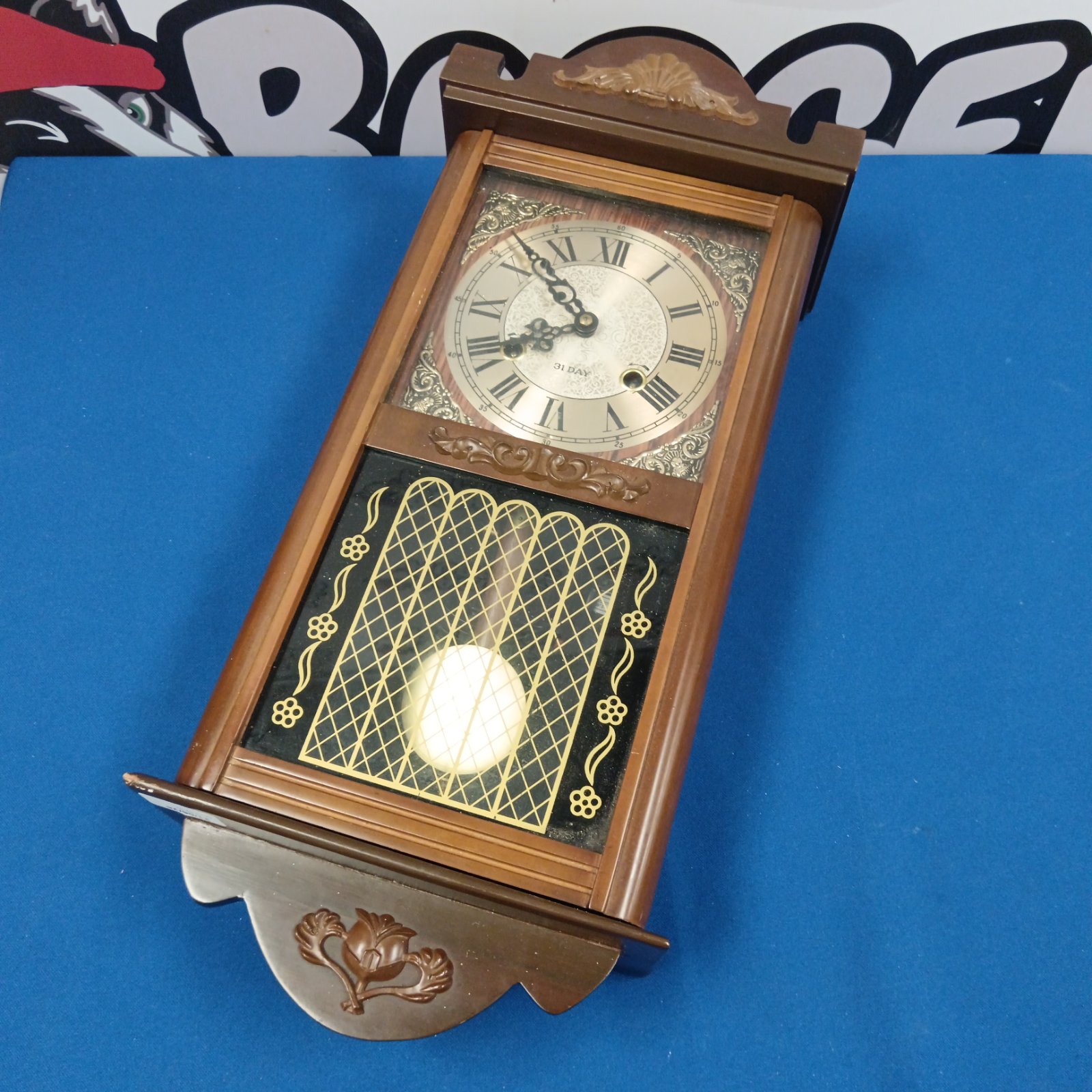 Vintage wooden wall clock with Roman numeral dial and pendulum view.