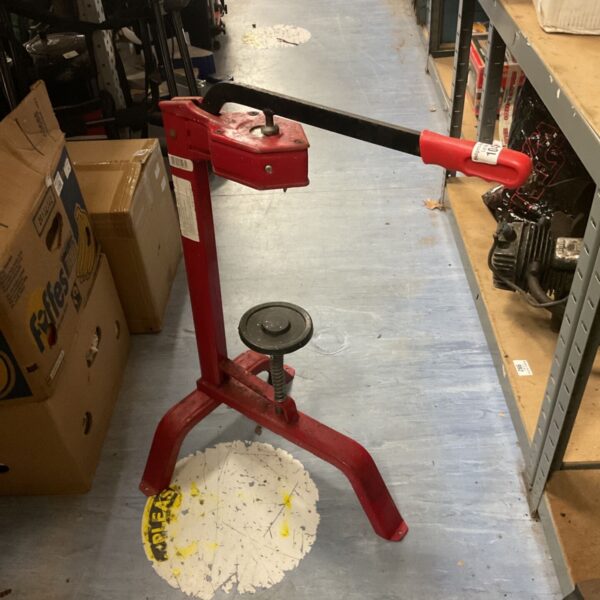 Vintage wine corking machine with red paint and lever mechanism.