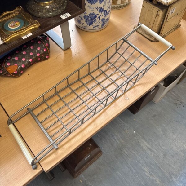 Vintage wire bath tray on a wooden surface.