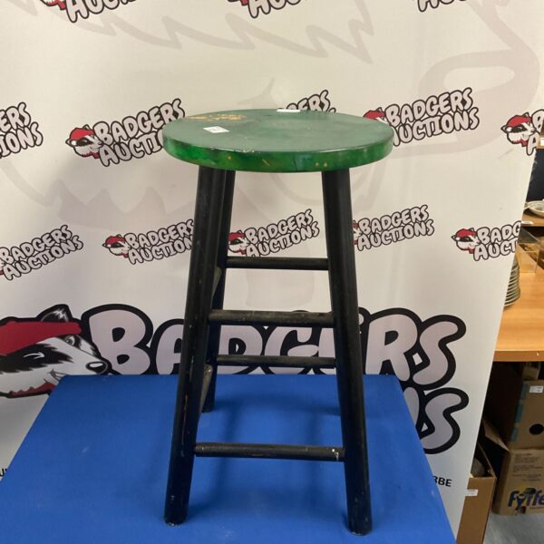 Vintage wooden bar stool with a green seat, rustic style.
