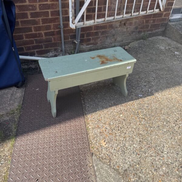 Small vintage wooden bench in a garden setting.
