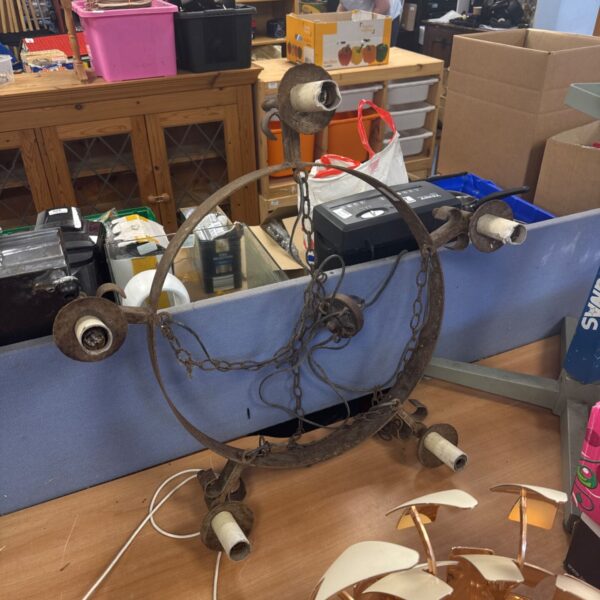 Vintage wrought iron chandelier awaiting restoration, antique lighting fixture.