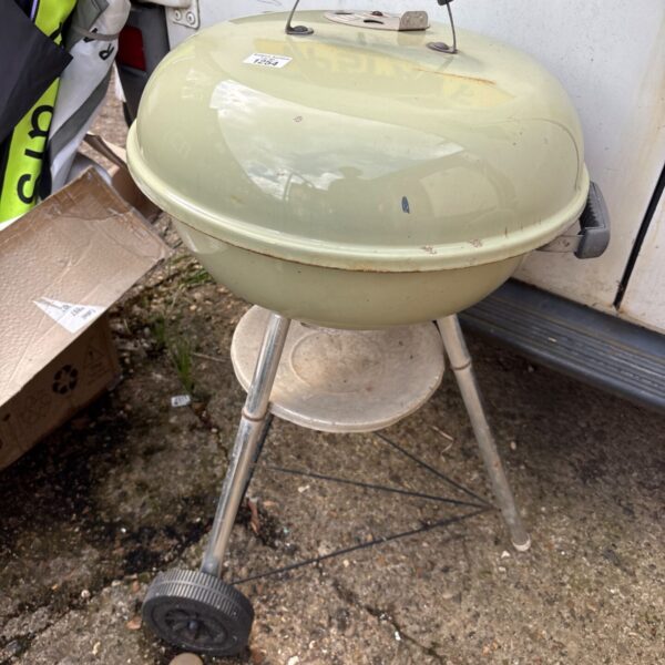 Vintage Weber Kettle charcoal grill in faded condition.