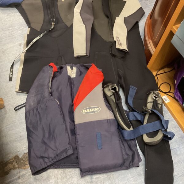 Lot of wetsuits, wet shoes, and a life vest for water sports.