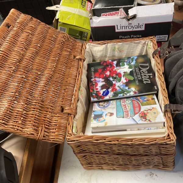 Wicker hamper overflowing with a collection of vintage cookbooks.