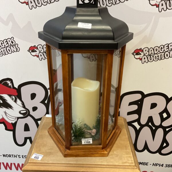 Large wooden lantern with a decorative wreath and glass panels.