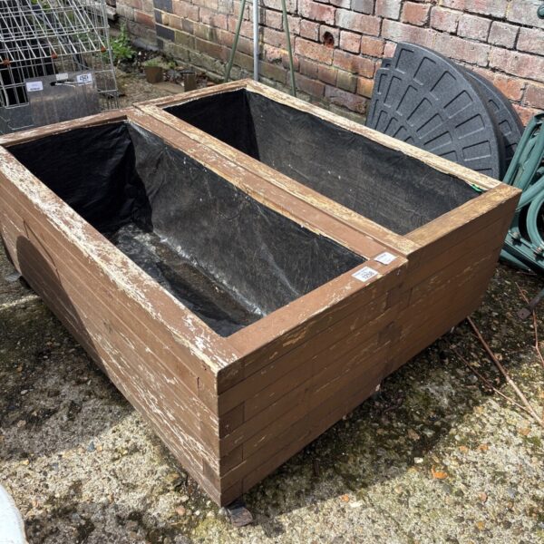Pair of weathered wooden planters on wheels for garden use.
