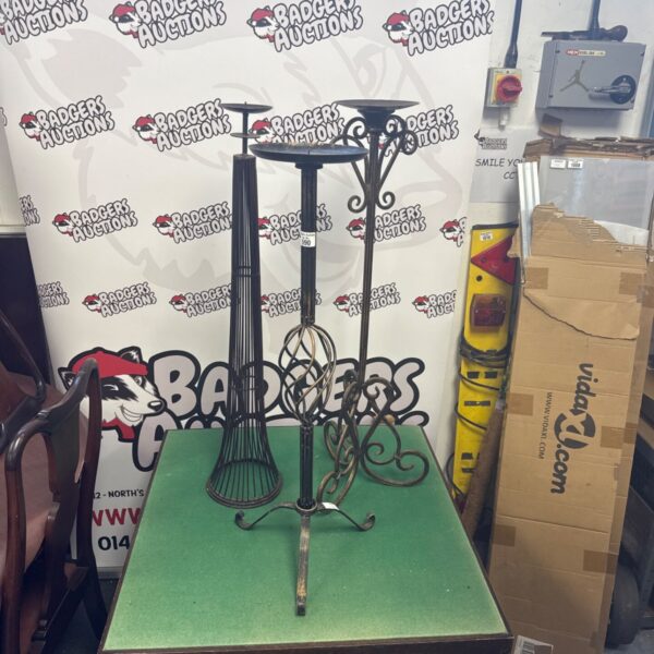 Three large vintage wrought iron candle holders with ornate designs.