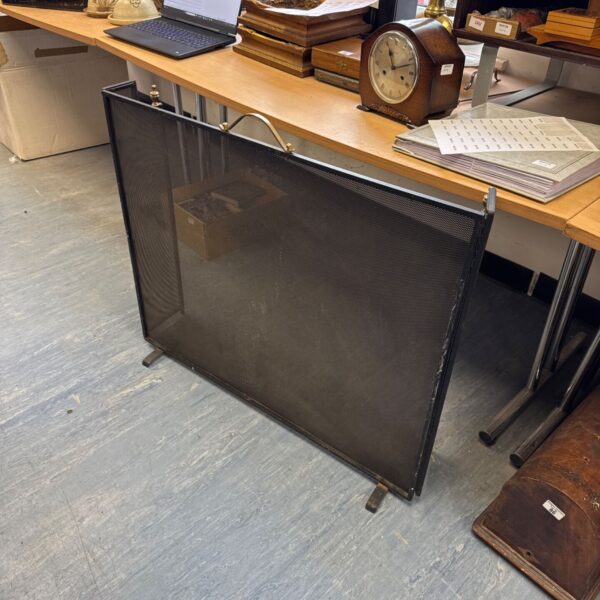 Vintage wrought iron fire screen with brass handle for fireplace safety.