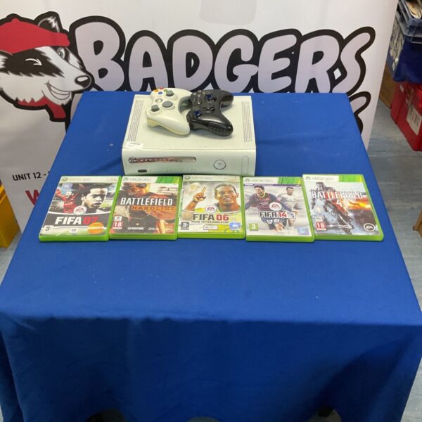 White Xbox 360 console with controllers and game cases displayed.