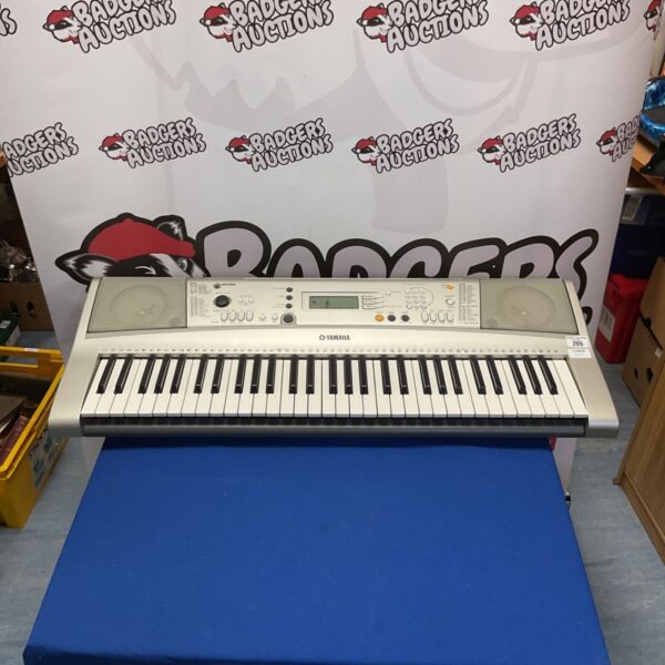 Yamaha YPT-310 electronic keyboard on a blue surface.