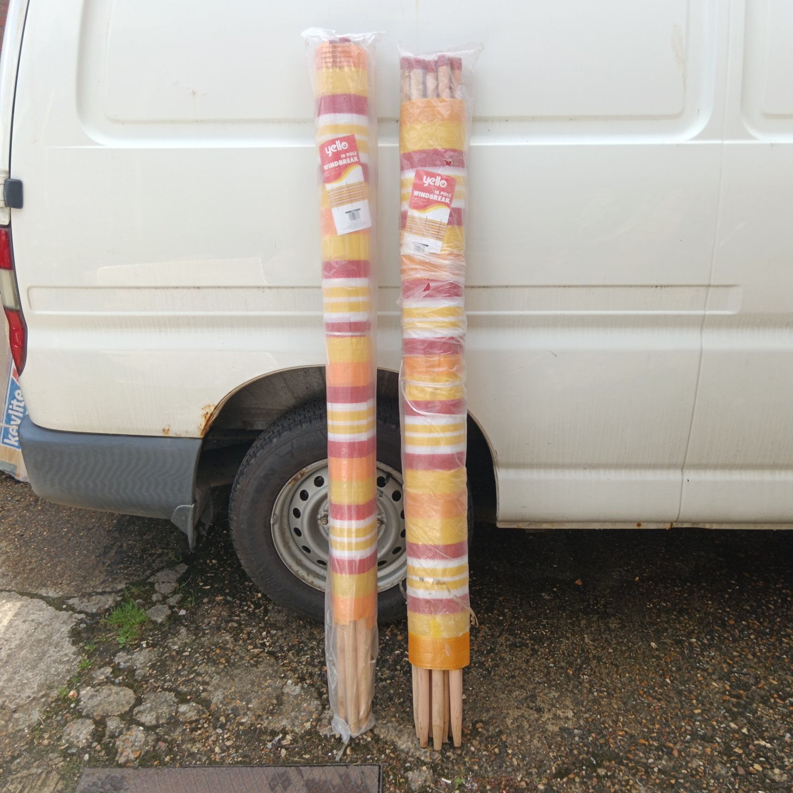 Two Yello 10 pole windbreaks leaning against a van.