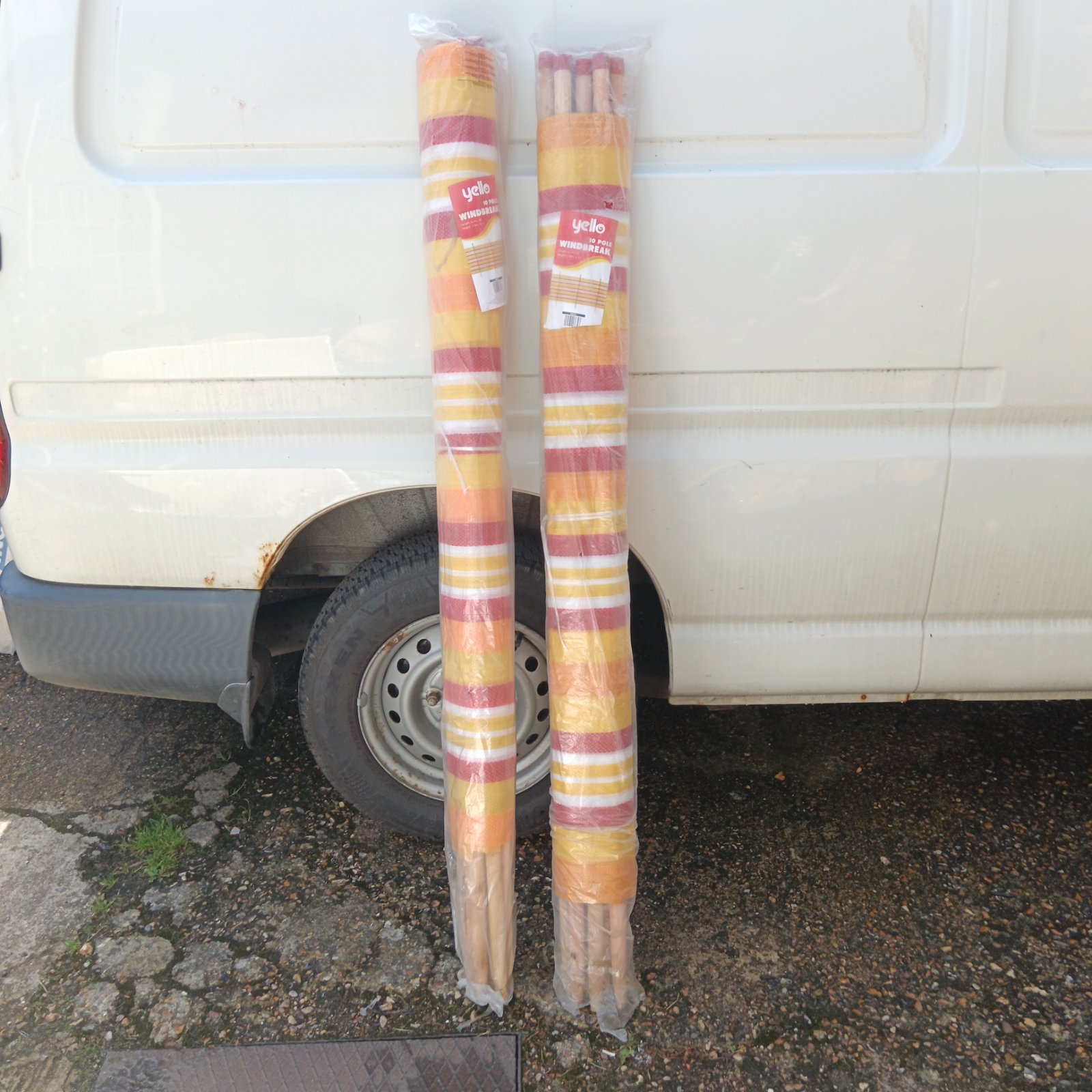 Two colourful Yello windbreaks standing against a van.