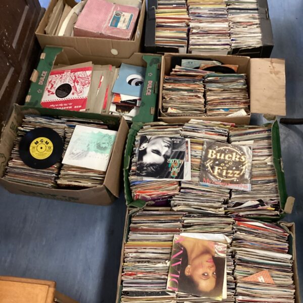 Stack of vintage 1950s rock and pop vinyl records in boxes.