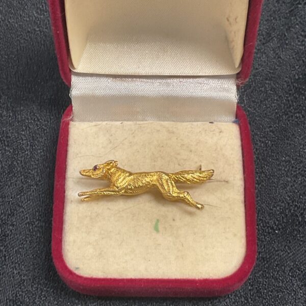 Vintage 9ct gold fox brooch with ruby eyes on display.