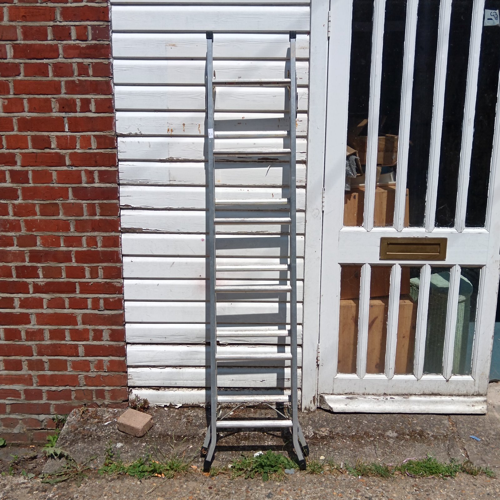Used Abru aluminium 3 way ladder leaning against a wall.