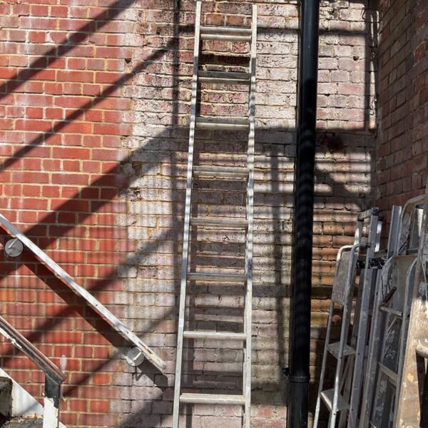 Aluminium double extension ladder leaning against a brick wall.