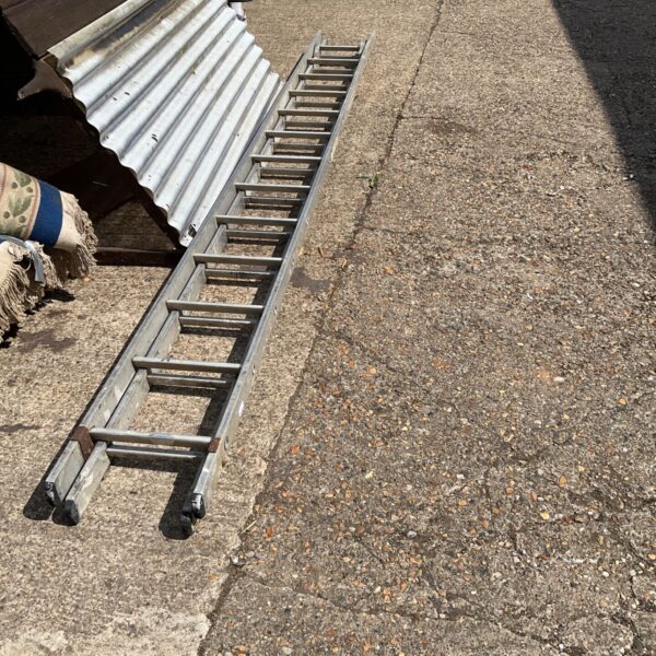Silver aluminium double extension ladder leaning against a wall.