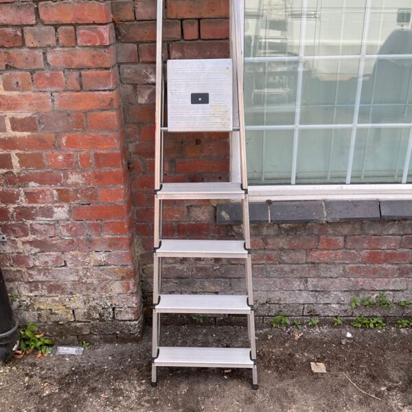 Aluminium five-step ladder leaning against a brick wall.