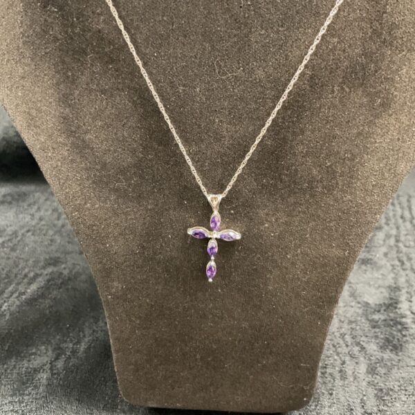 Silver cross necklace with a purple amethyst gemstone pendant.