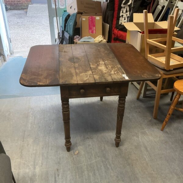 Antique drop leaf table with a wooden surface and turned legs.