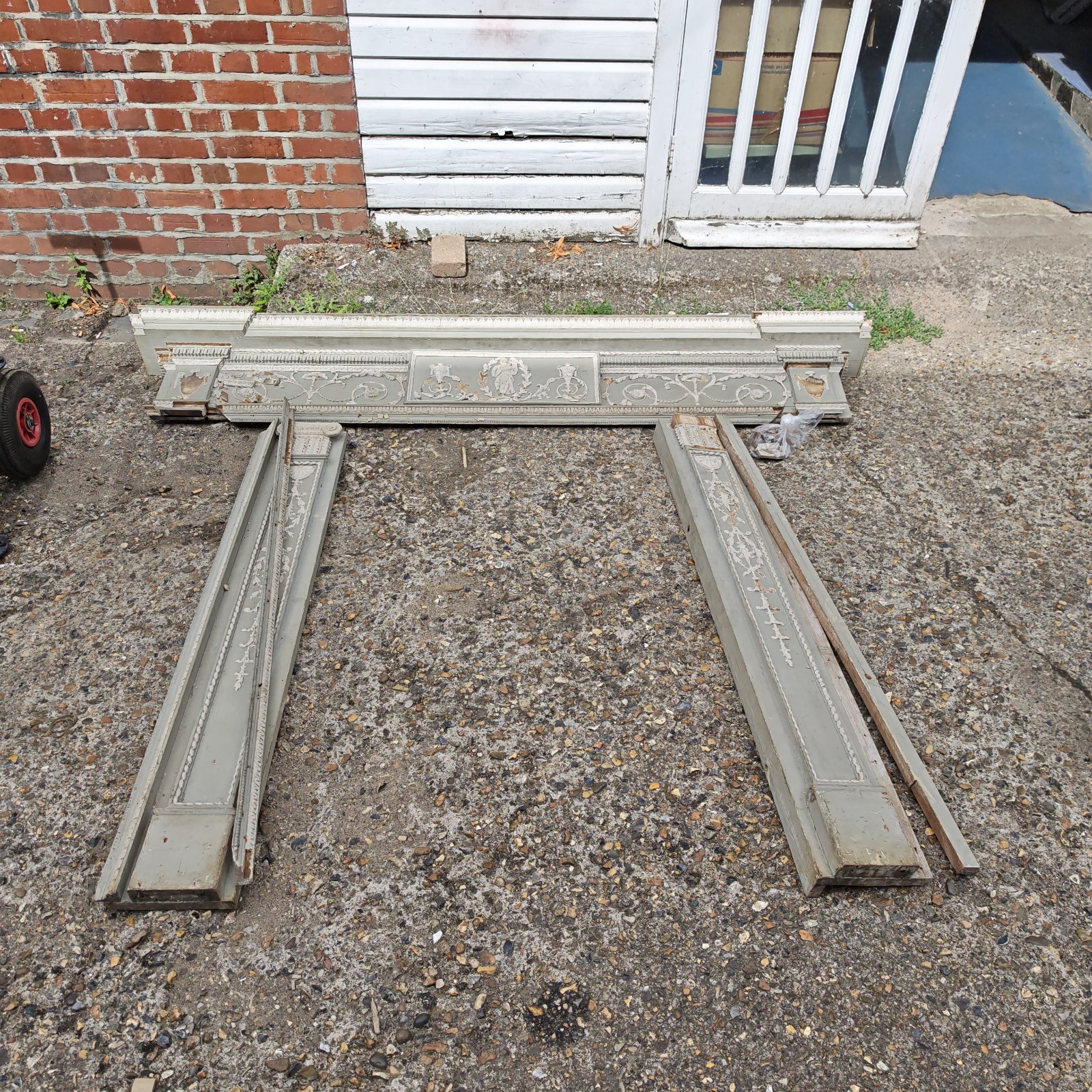 Antique wooden fire surround with jasperware detailing in a garden setting.