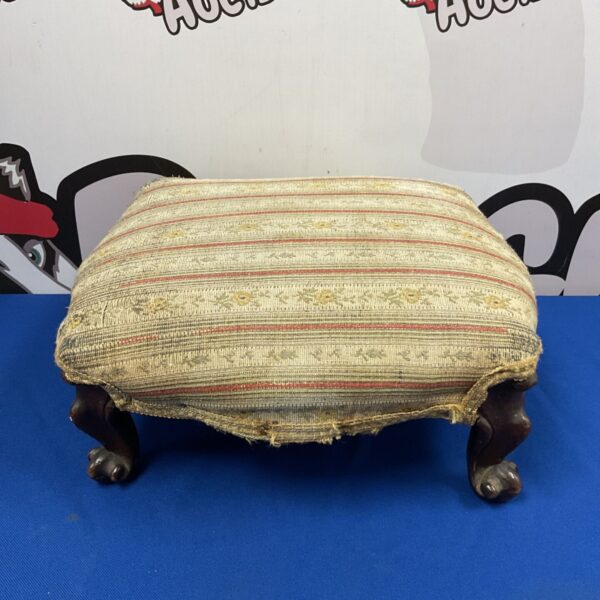 Antique footstool with striped upholstery and claw feet.