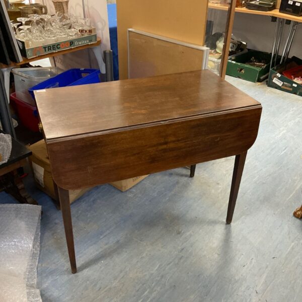 Antique mahogany Pembroke drop leaf table with drawers in a room setting.